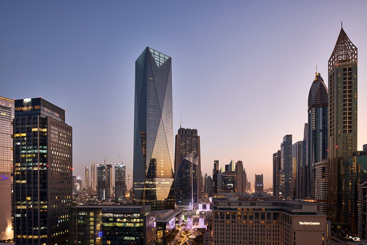 Das Foto zeigt den ICD Brookfield Place in Dubai bei Abenddämmerung, umgeben von der beleuchteten Skyline der Stadt.