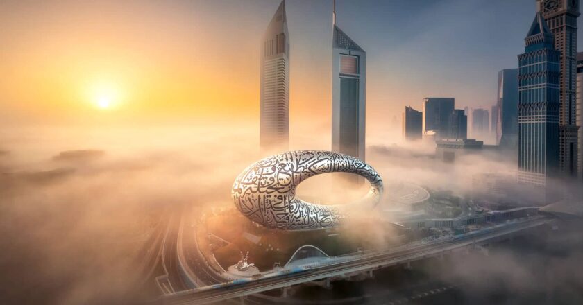 Das Foto zeigt ein atemberaubendes Bild von Dubais Museum der Zukunft, umgeben von Hochhäusern im Morgennebel, aufgenommen bei Sonnenaufgang.