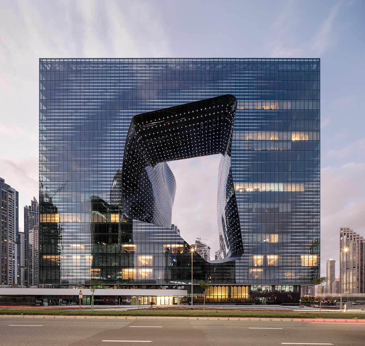 Das Foto zeigt The Opus in Dubai, ein modernes Gebäude mit einer einzigartigen, beleuchteten Aussparung in der Mitte, entworfen von Zaha Hadid.